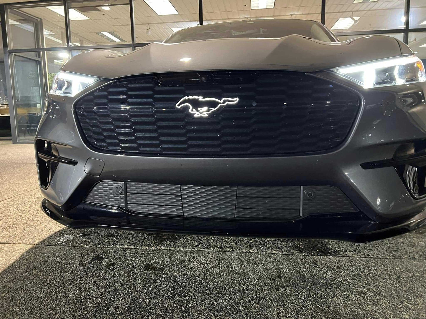 Front view of Mustang Mach-E GT with illuminated GT Pony Kit emblem on grille at night
