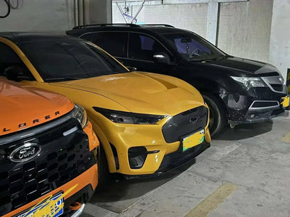 Yellow Ford Mustang Mach-E with Shelby Style Fiber Hood parked in a garage next to other vehicles