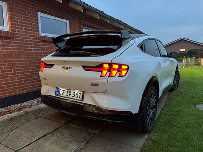 Ford Mustang Mach-E with black Rally Wing Spoiler installed on rear trunk, shown in outdoor setting at dusk
