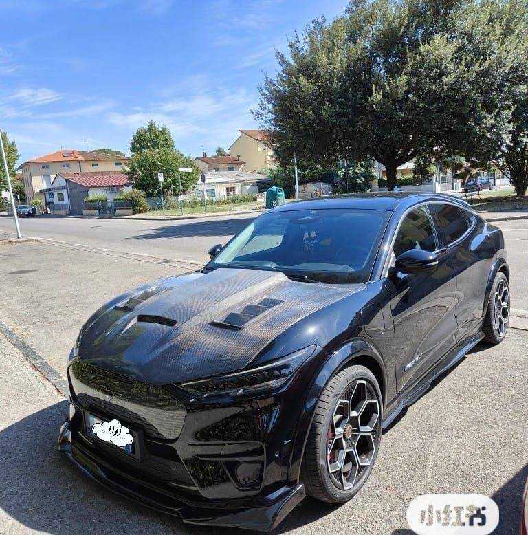 Black Mustang Mach-E with GT550 style wet carbon fiber hood featuring vents parked outdoors