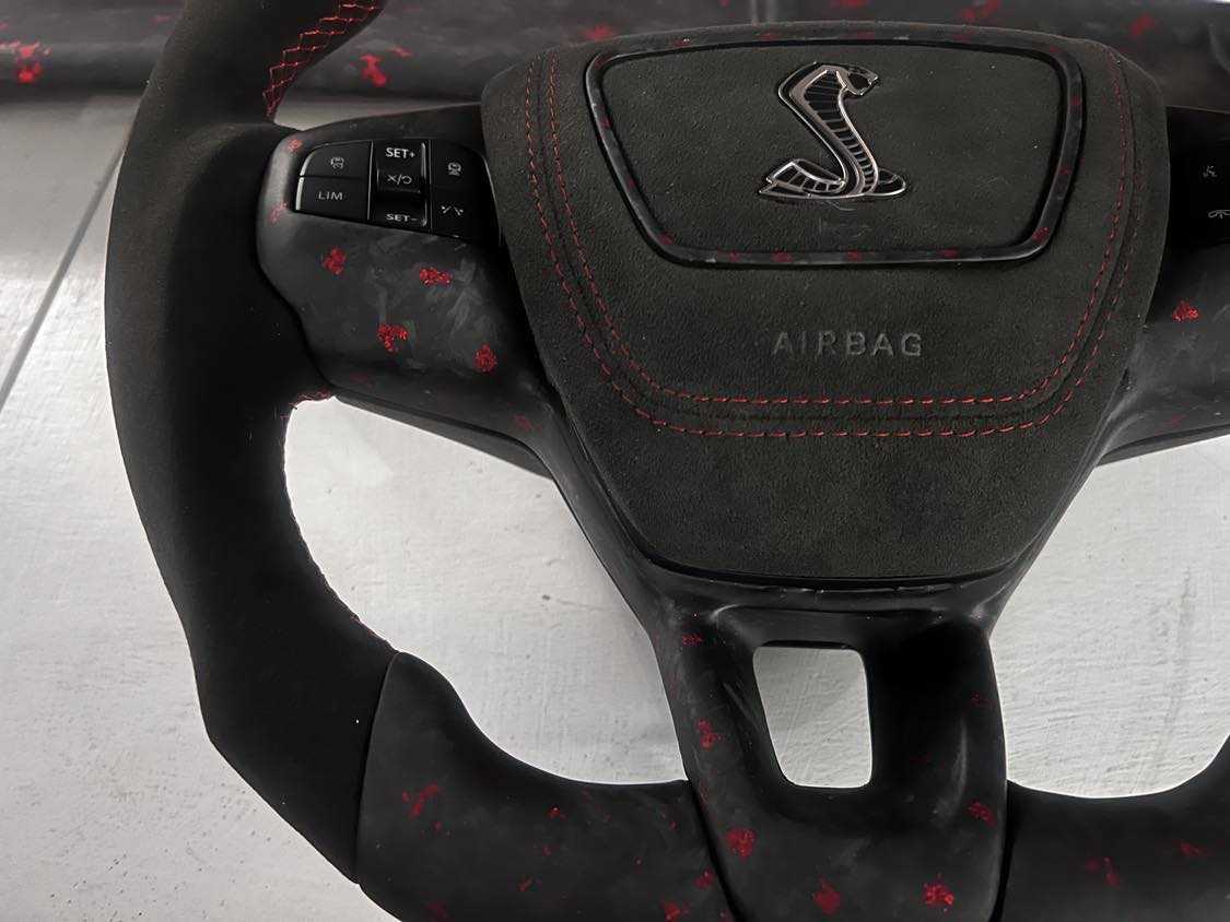 Custom made steering wheel for Mustang Mach-E with Alcantara grip, red stitching, and integrated multifunction buttons