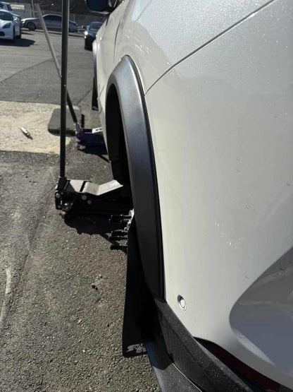 Close-up of a white car fitted with wider fender flares for enhanced tire clearance and aggressive stance