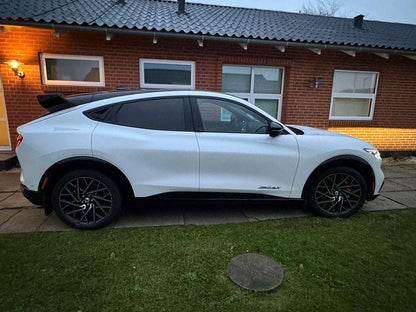 White Ford Mustang Mach-E with installed black Rally Wing Spoiler parked in front of a brick house