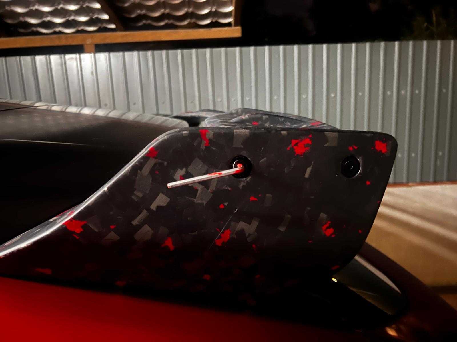 Close-up of a carbon fiber Rally Wing Spoiler with red accents installed on a Ford Mustang Mach-E rear in a garage setting