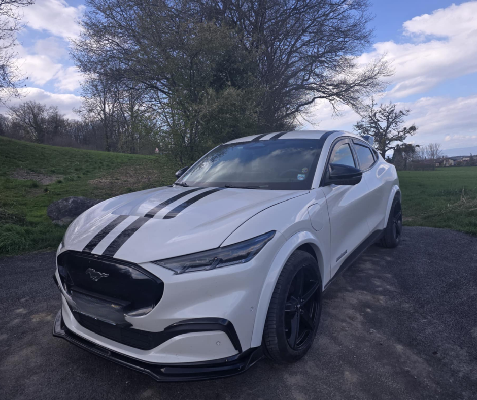 White Ford Mustang Mach-E with Shelby Style Fiber Hood and black racing stripes parked outdoors