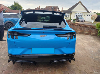Blue Mustang Mach-E GT with black rear diffuser installed, parked in a driveway.