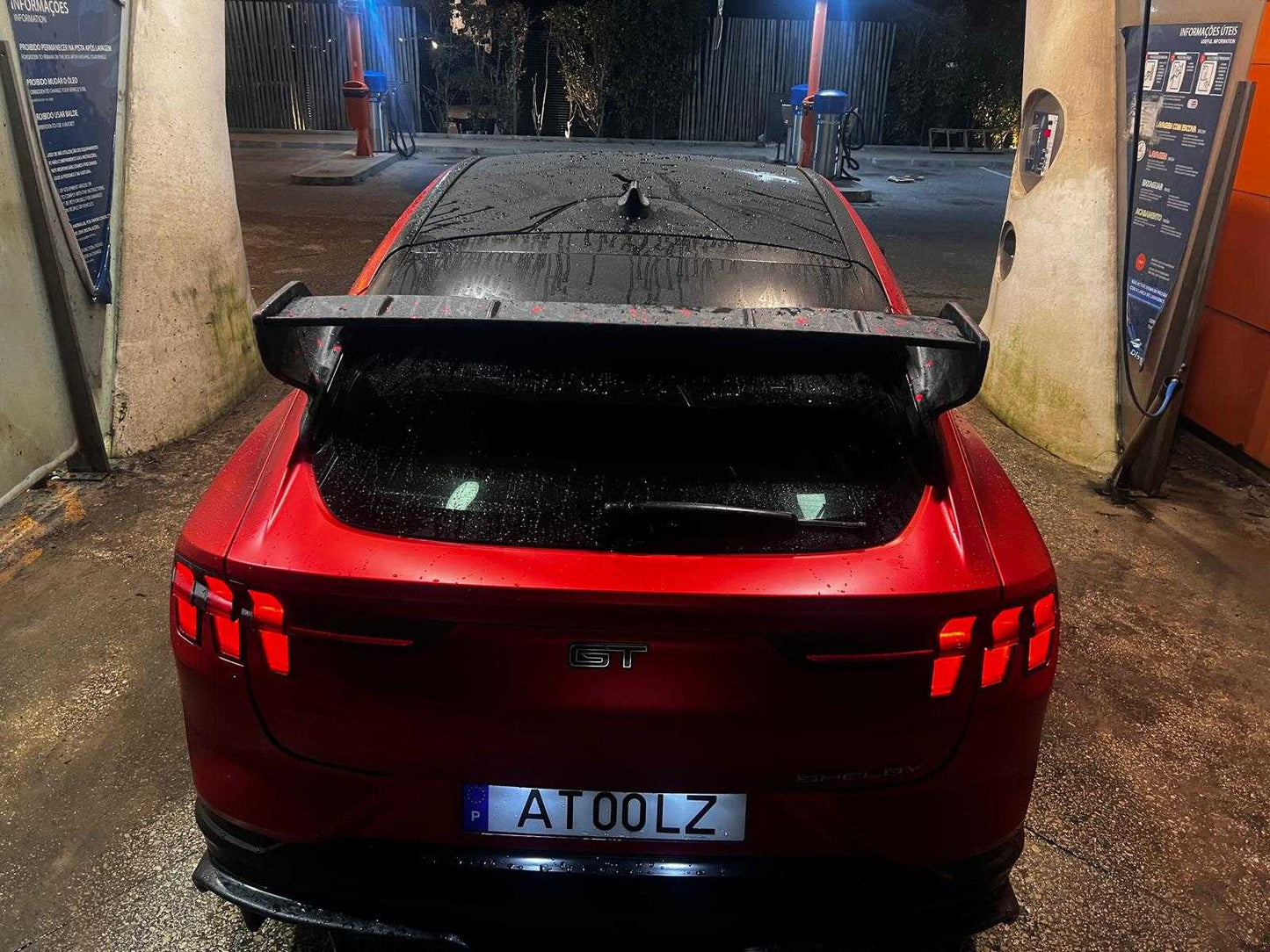 Rear view of red Ford Mustang Mach-E with black Rally Wing Spoiler installed at gas station