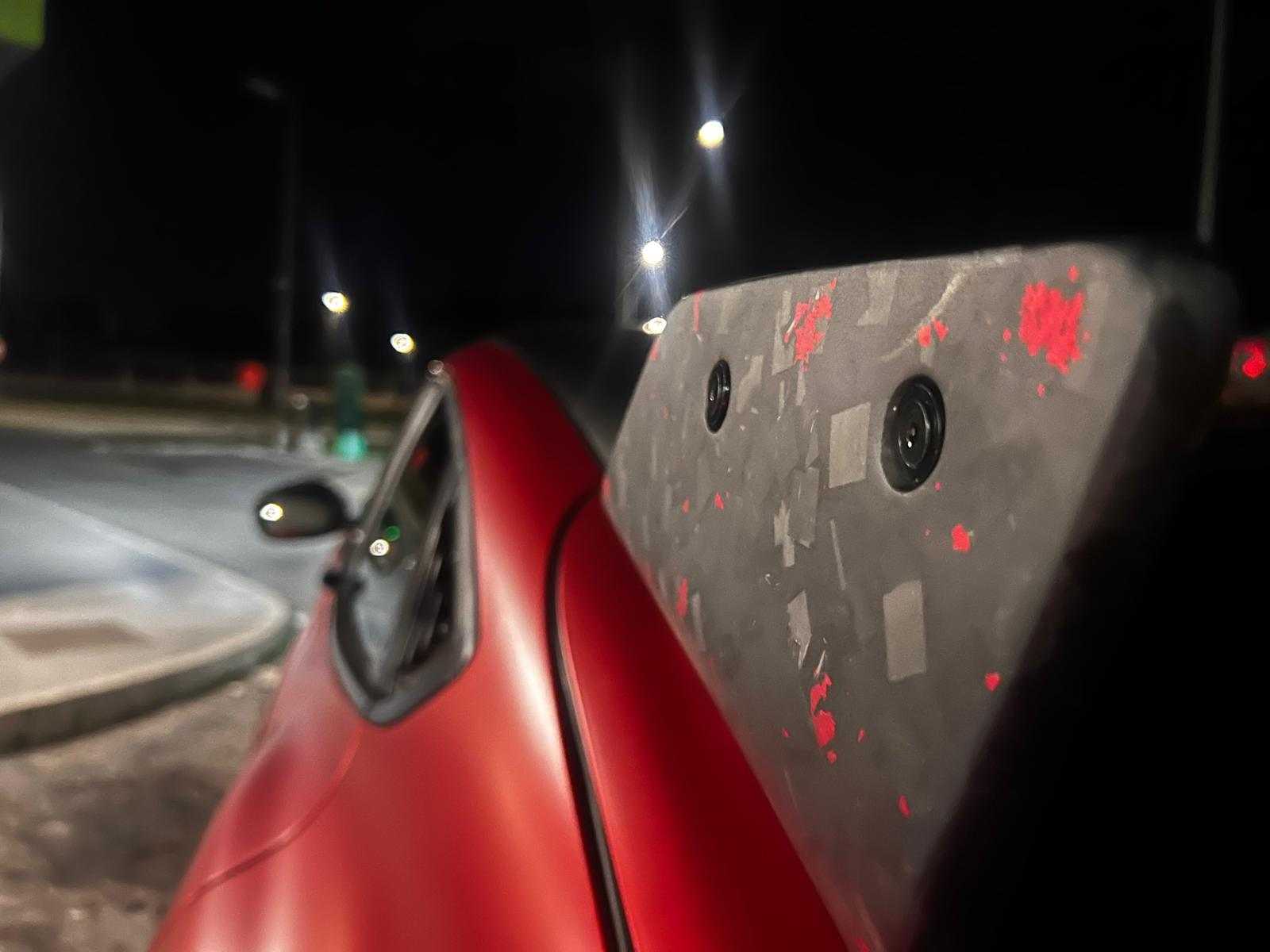 Close-up of rally wing spoiler installed on red Ford Mustang Mach-E at night with street lights in background