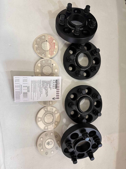 Set of forged aluminum wheel spacers with installation instructions and adapters in black finish